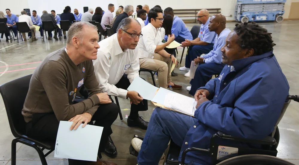 Two men talking another man in a wheelchair