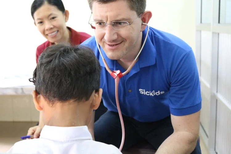 Man wearing a Stethoscope examining a child