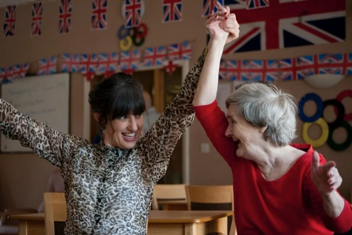 A woman dancing with an elderly woman, both smiling