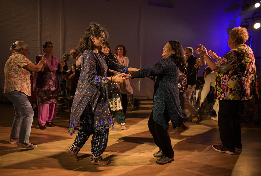 Two women performing a dance routine while an audience applauds