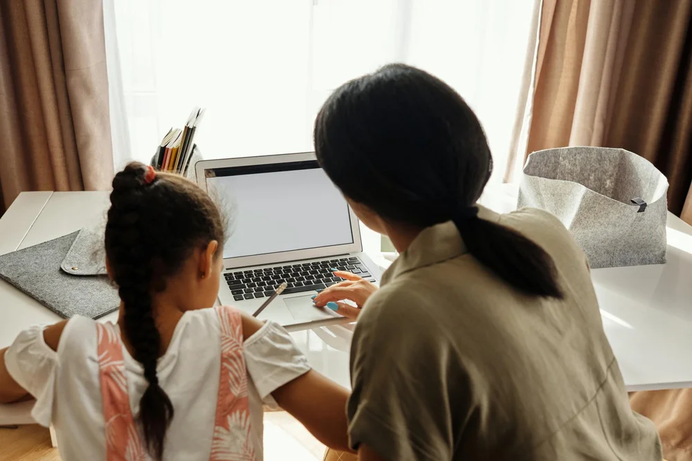 A child and adult sat at a desk completing homework together